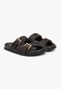 Black fur-lined slide sandals with two adjustable straps featuring gold-tone metal buckles. Soft texture with a flat rubber sole.