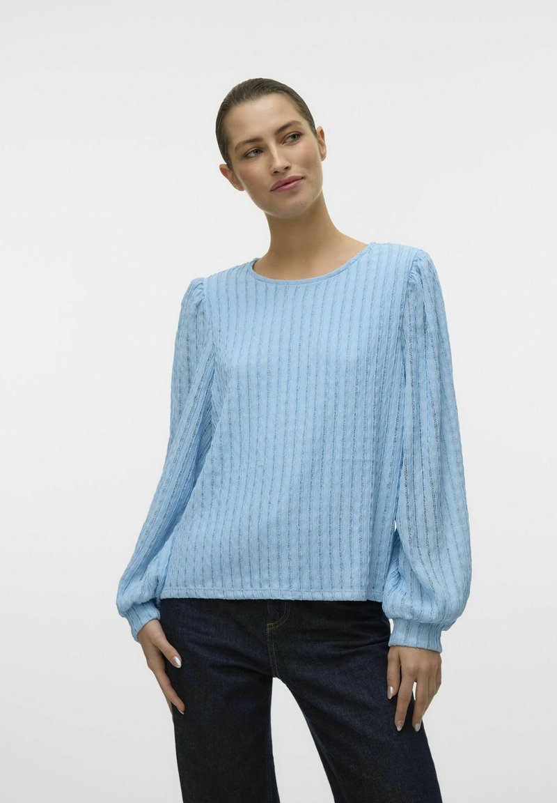 Heledad hele sinine pikakä sleeves palliga pluus, millel on vertikaalne sooniline tekstuur, ümar kaelus ja kogutud varrukate mansetid. Kombineeritud tumedate teksadega.