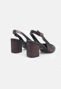 Décolleté a slingback con una finitura bronzo scuro metallico, caratterizzati da un tacco a blocco e una cinghia regolabile alla caviglia. Texture liscia con dettagli minimi.