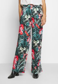 Wijde broek met bloemenprint op een zwarte achtergrond, met levendige rode en groene tropische patronen, elastische tailleband en zijzakken.
