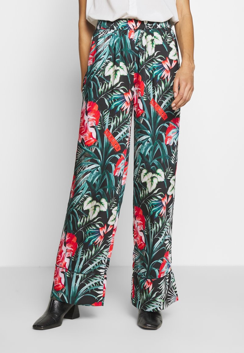Wijde broek met bloemenprint op een zwarte achtergrond, met levendige rode en groene tropische patronen, elastische tailleband en zijzakken.