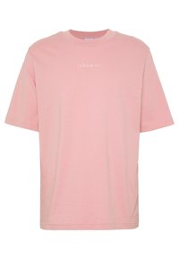 Vaaleanpunainen puuvillapaita lyhyillä hihoilla, pyöreä pääntie ja huomaamaton valkoinen Adidas-logo ommeltuna eteen. Sileä tekstuuri kauttaaltaan.