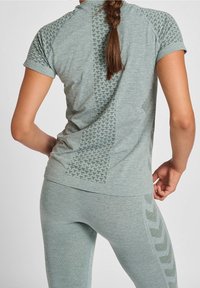 Szary sportowy top z krótkim rękawem o fakturowanym wzorze, w zestawie z dopasowanymi legginsami z motywem jodełki po bokach.