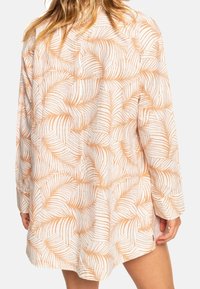 Kurzarmhemd aus leichtem Stoff mit einem off-weißen Grund und orangefarbenen Palmenblattmustern in lockerer, oversized Passform.