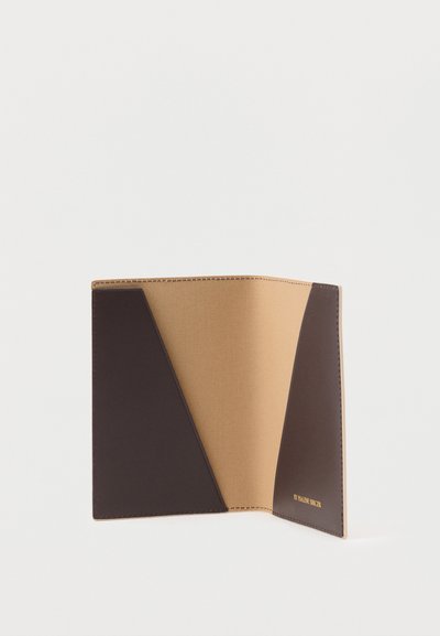 Ανοιχτό δίχρωμο καφέ και μπεζ δερμάτινο θήκη διαβατηρίου με διαγώνιες θήκες για κάρτες και χρυσό κείμενο "BY MALENE BIRGER" στο κάτω δεξιά μέρος.