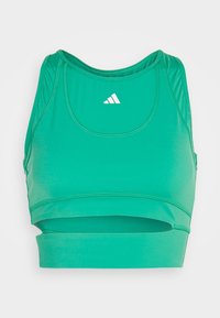 Brassière de sport verte Adidas avec style dos nageur et logo blanc centré à l’avant sur fond uni.