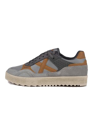 Zapatillas grises con acentos marrones, fabricadas con malla y ante. Presentan una suela beige texturizada y paneles laterales perforados para mayor transpirabilidad.