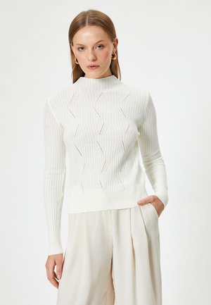 Pull blanc côtelé à col montant, avec des motifs en vagues et des accents texturés. Matière douce avec des manches longues et un ourlet ajusté.