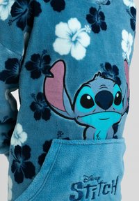 Felpa blu in pile con design di Stitch, grandi orecchie, motivi floreali hawaiani e tasca frontale con dettaglio "Disney STITCH".