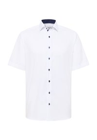 Camicia bianca a maniche corte con colletto, dotata di bottoni blu navy e un motivo a pois blu navy all'interno del colletto.