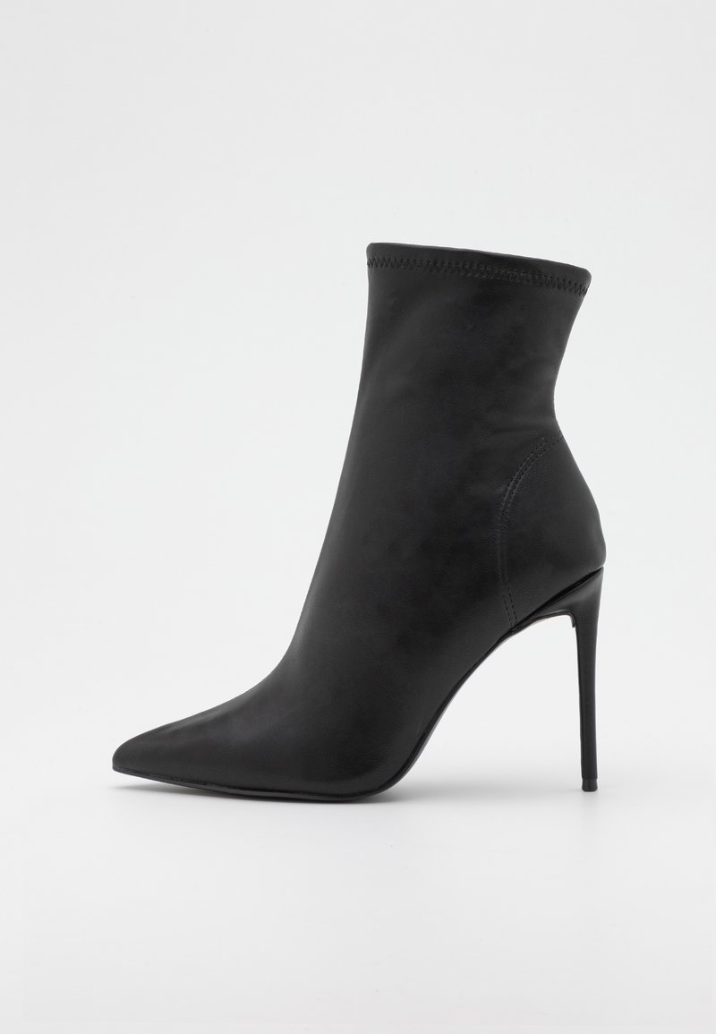 Zwarte enkelboot van glad kunstleer, met een spitse neus en een dunne stilettohak. Strakke, aansluitende vormgeving zonder zichtbare bevestigingsmiddelen.