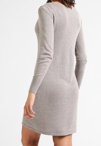 Graues gestricktes Pulloverkleid mit langen Ärmeln, Rundhalsausschnitt und figurbetonter Silhouette, versehen mit gerippten Bündchen und glatter Textur.