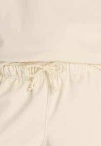 Light beige sweatshirt and sweatpants with a drawstring waist, featuring a smooth texture and simple, minimalist design.