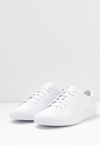 Vita lädersneakers med en slät yta, rund tå, runda snören och en minimalistisk design. Gummisulor med små mönster i sulan.
