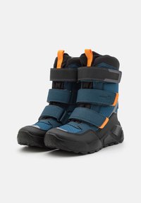 Blue and black ankle boots with textured material, Velcro straps, orange accent, and rugged black sole for durability.