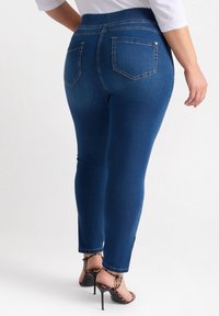 Vaqueros skinny de denim azul con una cintura alta, cinco bolsillos y un ajuste ceñido. Combinados con sandalias de tacón alto con estampado de leopardo negro.