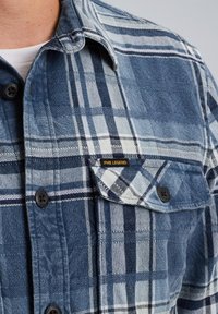 Camicia a quadri blu e bianca con tasca sul petto dotata di pattina e etichetta PME Legend sulla tasca.