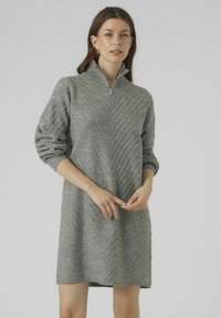 Abito grigio a maglia con colletto alto con zip. Presenta un motivo a rombi testurizzato e maniche lunghe, leggermente gonfie.