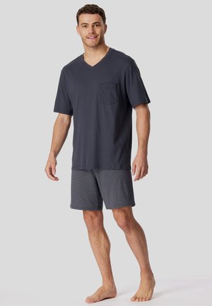 Dark gray V-neck t-shirt with a chest pocket, paired with patterned shorts featuring small white dots on a navy background.
