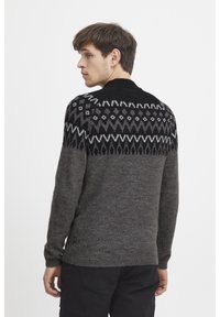 Wollpullover mit einem dunkelgrauen Körper und einem schwarzen gemusterten Einsatz, der geometrische Formen zeigt. Gerippter Kragen und Bündchen, lockere Passform.