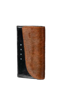 Cartera de cuero negro con una solapa de pelo marrón, que presenta una textura suave, forma elegante y el logo "BREE" en relieve en azul claro.