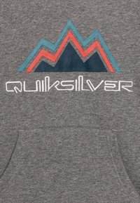 Grauer Sweatshirt mit einem Grafikdesign von drei Bergen in Teal, Rot und Dunkelblau, mit "Quiksilver" in Weiß darunter gestickt.