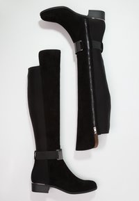 Bottes noires montantes en cuir suédé et tissu, avec une fermeture éclaire sur le côté, un accent de sangle et un talon bas.