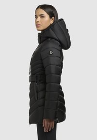 Sort pufferjakke med quiltet tekstur, lynlåslommer og aftagelig hætte. Inkluderer justerbart bælte og logo detalje.