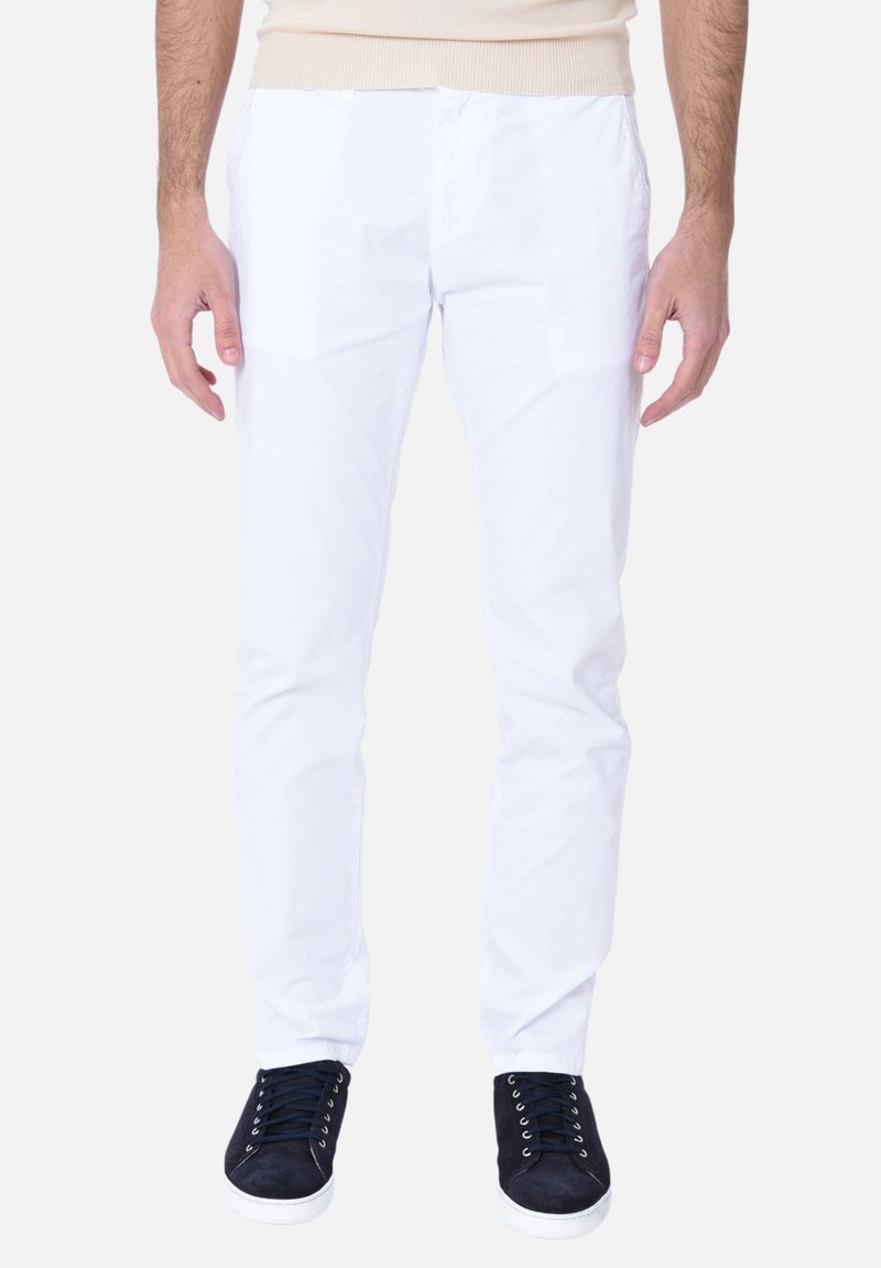 Pantaloni bianchi in cotone slim fit, dotati di tasche frontali e chiusura con bottone, abbinati a sneakers in camoscio blu navy.