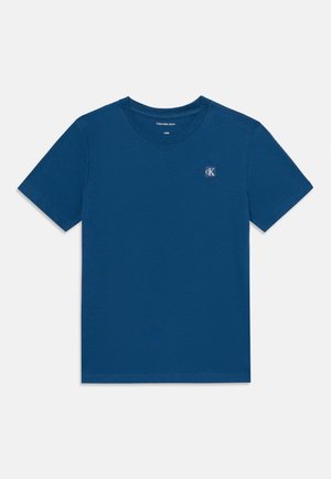 Tricou din bumbac albastru, cu guler rotund, mâneci scurte și un mic logo CK în partea stângă sus. Textură netedă, țesătură ușoară.