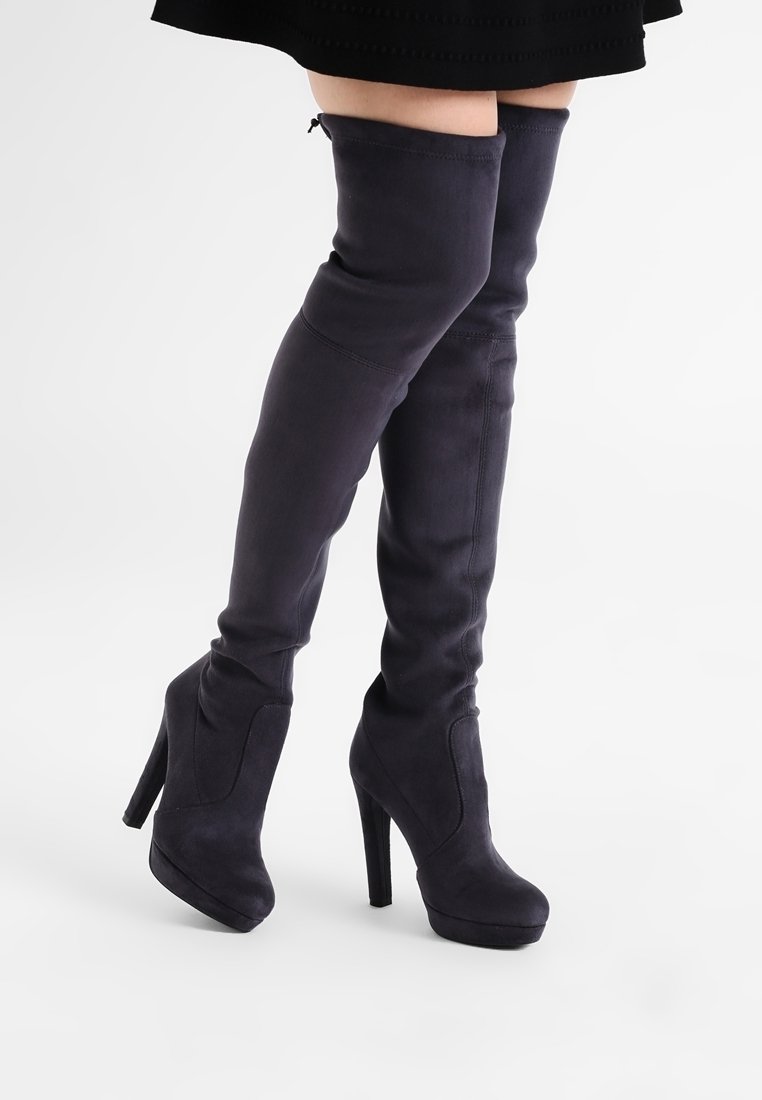 Stivali in suede viola scuro fino al ginocchio con punta a mandorla e alto tacco a stiletto; texture liscia e cuciture decorative minime.