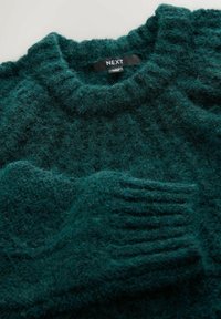 Tavi pulóver bordás kerek nyakkivágással, puha és texturált anyagból, látható varrásokkal a mandzsettákon. Márkajelzés látható.