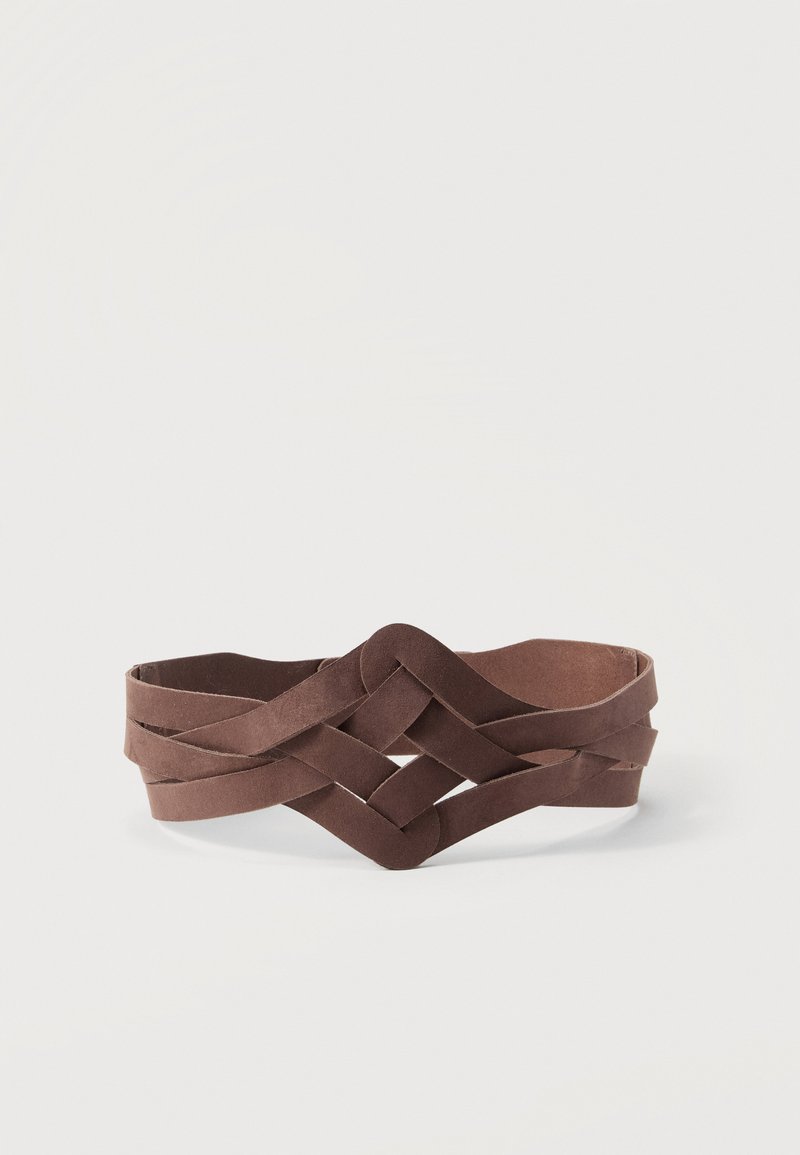 Ceinture en cuir marron avec un dessin tissé et entrelacé posée à plat sur un fond blanc.