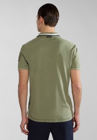 Oliwkowa koszulka polo z krótkim rękawem, z kontrastowym kołnierzykiem, strukturalnym materiałem, bocznymi wwentylacjami oraz naszywką z logo na górnej części pleców.