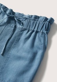 Pantalon bleu clair avec ceinture élastique et cordon de serrage noué, présentant des coutures détaillées et une texture de tissu douce.