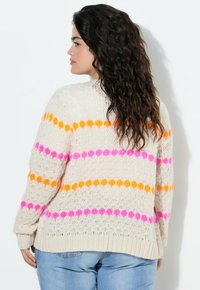 Strikket sweater i cremefarvet med pink, orange og gule vandrette striber. Har en afslappet pasform og ribbet kant. Struktureret stingmønster.