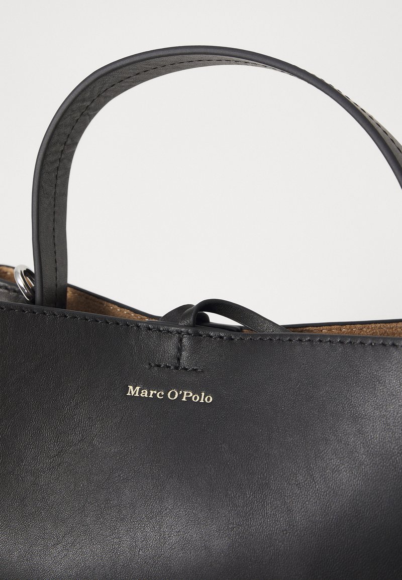 Schwarze Ledertasche mit glatter Oberfläche, dezenten Stickdetails und einem goldenen Logo "Marc O'Polo" auf der Vorderseite.