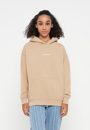 Beige pullover hoodie made of soft fabric, featuring a front kangaroo pocket, ribbed cuffs, and simple white text logo on the chest.