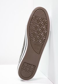 Semelle extérieure de basket en caoutchouc gris avec un motif texturé, une bande intermédiaire blanche et un logo. Présente un profil en diamants pour une meilleure adhérence et durabilité.