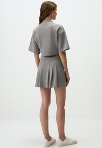 Grau geripptes Zweiteiler-Set bestehend aus einem kurzärmeligen Oberteil und einem Faltenrock, gefertigt aus weichem Stoff, mit minimalistischem Design und lässiger Passform.