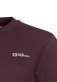 Donkerpaarse Jack Wolfskin shirt met logo van een pootafdruk op de linkerborst, met ronde hals, close-up van het bovenste gedeelte.
