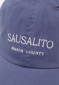 Navy blue baseball cap with a curved brim. Features white embroidered text: "SAUSALITO" and "MARIN COUNTY." Made of textured fabric.