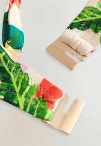 Lillemustriga kangasrihm roheliste lehtede ja roosade aktsentidega, millel on kuldsed metallist detailid ja otstes õmmeldud viimistlus.