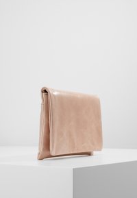 Clutch en cuir rose avec une texture lisse, de forme rectangulaire et une fermeture à rabat, exposée sur un fond blanc minimaliste.