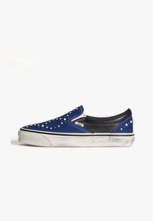 Sneaker slip-on blu e nero con suola bianca, decorata con piccoli borchiette bianche e argento, leggermente consumata sulla suola.