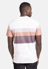 Kortermet T-skjorte i hvit med horisontale striper i nyanser av fersken, lavendel og grå; har rund hals og strukturert stoff.