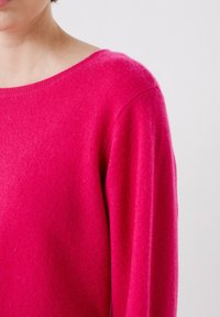 Maglione in cashmere fucsia con scollo ampio, polsini leggermente a costine e una consistenza morbida, caratterizzato da una vestibilità rilassata e un design minimalista.