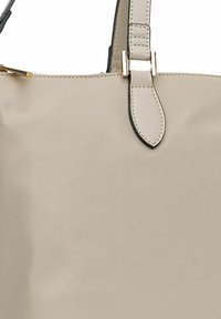 Tote bag beige chiaro con una texture liscia, doppi manici, hardware in tonalità oro e una silhouette strutturata con accenti scuri.