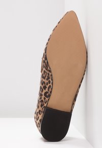 Chausson à bout pointu avec un dessus en imprimé léopard, semelle beige lisse et talon noir texturé, taille 37, incliné sur un fond blanc.