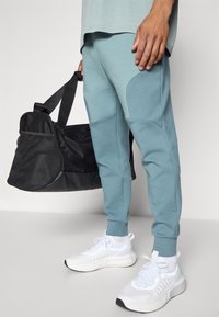 Under Armour UNSTOPPABLE FLEECE - Tracksuit bottoms - jasper blue/serpentine/black